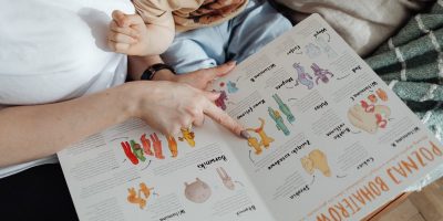 A comforting moment of a mother reading a colorful picture book with her child.